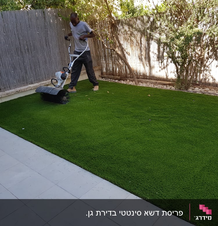 אדם משתמש במכונה לטיפוח דשא בגינה